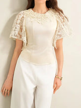 Cream-colored satin lace trimmed short sleeve blouse with delicate floral lace cap sleeves and a soft sheen finish