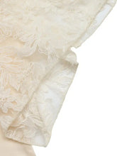 Cream-colored lace trimmed short sleeve blouse with intricate floral patterns and soft flowing texture