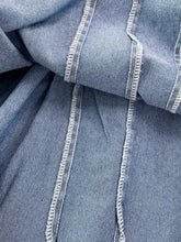 Blue denim a-line mini dress featuring white zigzag stitching along the seams for a stylish denim dress look