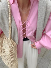 Pink oversized shirt with lace-up front and satin-like finish featuring matching pink lacing