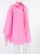 A vibrant pink oversized shirt featuring long sleeves and a lace-up front detail for a stylish look