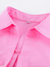 A vibrant pink satin oversized shirt with a crisp collar and subtle stitching details featuring a lace-up front