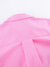 A vibrant pink oversized shirt with a lace-up front, smooth texture, classic collar, and structured shoulder seams