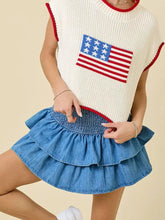 White knit sleeveless top with red trim and american flag patch paired with layered ruffle smocked waist denim skirt