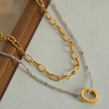 Layered titanium steel necklace with 18k gold-plated chain, twisted ring pendant, silver beads, and clear crystals