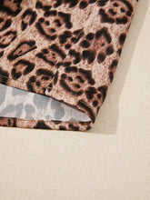A close-up of a soft textured leopard bow tie puff sleeve blouse fabric with brown and black spots