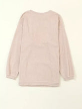 A soft blush pink ribbed knit long-sleeved top with relaxed fit and rounded neckline perfect for oversized fit styling