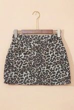 Leopard denim mini skirt in black and gray leopard print denim hanging on a wooden hanger