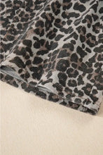 A close-up of a leopard denim mini skirt in black and brown spots on a light gray background showing the mini skirt details
