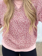 A soft pink leopard-print relaxed fit sweatshirt with v-neck and ruffled sleeves made of slightly stretchy fabric