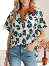Women’s short sleeve blouse with bold green and pink leopard print on white and an orange button collar detail