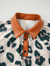 Women’s cream leopard print short sleeve blouse with bold green and pink spots and orange faux leather collar accents