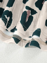 A flowing dress with cream base and bold abstract patterns, paired with a leopard print short sleeve blouse