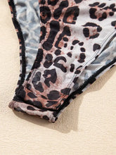 A close-up of leopard print bikini bottom with black and brown spots and mesh trim paired with long sleeve mock neck bodysuit