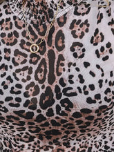 A delicate gold chain necklace with a circular pendant paired with a leopard print long sleeve mock neck bodysuit