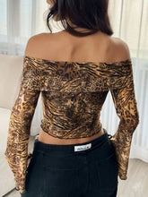 A sheer long-sleeved off-shoulder crop top with bold brown and black leopard print and tiger stripe pattern