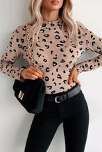 Black quilted crossbody bag with gold-tone hardware and chain strap styled with leopard print sheer mesh bodysuit