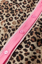 Leopard print short sleeve shirt with vibrant pink buttoned placket and white diagonal stripes on leopard print fabric