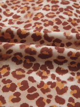 Cream-colored leopard print smocked notched blouse with bold rust and mustard yellow pattern on fabric