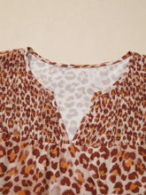 Leopard print smocked notched blouse with brown and orange pattern and smocked neckline featuring white inner lining
