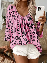 Pink leopard-print blouse with three-quarter sleeves and ruffled neckline featuring a v-neck design