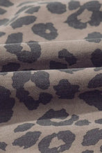 Tan fabric with dark gray leopard print on the round neck puff sleeve detail of a denim dress