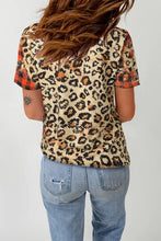 Woman in leopard round neck short sleeve T-shirt with plaid accents and distressed jeans