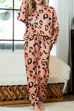 A cozy peach-colored leopard print lounge set with long sleeve round neck top and drawstring pants in satin fabric