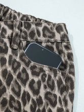 A black smartphone in the front pocket of leopard straight loose denim jeans with a loose leg fit