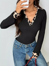 Black ribbed knit bodysuit with leopard trim ribbed neckline and cuffs in a stylish long-sleeve design