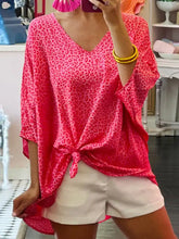 A vibrant pink leopard v-neck blouse with three-quarter sleeves tied at the waist for a casual look