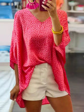 A vibrant pink leopard-print blouse with a loose fit and three-quarter sleeves featuring a v-neck design