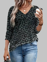 Woman in gray leopard print long sleeve V-neck T-shirt and blue jeans