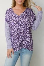 Woman in purple leopard long sleeve V-neck T-shirt with twisted hem and light wash jeans