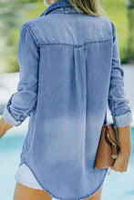 Light blue denim shirt with button-down front, rolled-up sleeves, collar, and chest pockets