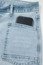 A black smartphone in the back pocket of light wash utility pocket straight leg denim jeans shown from the back side