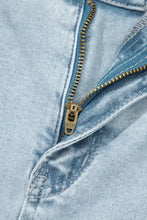 A brass-colored zipper with metallic pull tab on light wash utility pocket straight leg jeans in light wash denim
