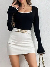 Long sleeve bodysuit in black with white contrast trim and bell cuffs paired with white faux leather mini skirt