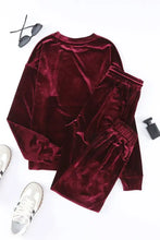 A deep burgundy velvet two-piece lounge set with relaxed fit, long sleeve length top, and elastic cuff joggers at the natural waistline