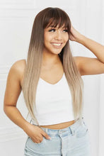Smiling woman in long straight synthetic wig with ombre brown to blonde hair and bangs
