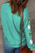 A long-sleeved teal tunic with shamrock appliques on the arm.