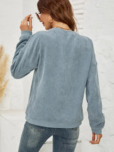 Woman in MAMA Graphic Round Neck Sweatshirt with long sleeves and blue jeans