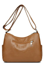 Tan leather crossbody bag with zipper details and adjustable strap