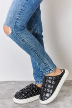 Person in distressed blue jeans wearing Melody Puffer Plush Slippers with platform heel height