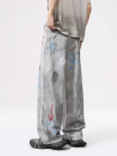Men’s distressed graffiti print wide leg jeans in gray with red blue and black paint splashes and graffiti markings