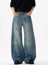 Men’s distressed loose fit jeans in faded blue denim with wide-leg cut and intentional distressing at the knees