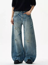 Men’s distressed loose fit jeans in faded blue denim with wide-leg cut and intentional knee distressing