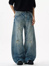 Men’s distressed loose fit jeans wide-leg denim with faded blue wash and intentional distressing at the knees
