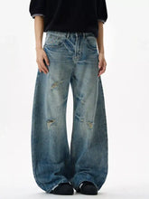 Men’s distressed loose fit jeans in faded blue denim with wide legs and knee distressing for casual wear