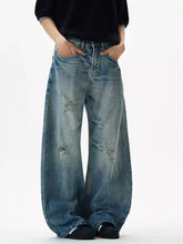Men’s distressed loose fit wide-leg jeans in faded blue denim with intentional distressing at the knees